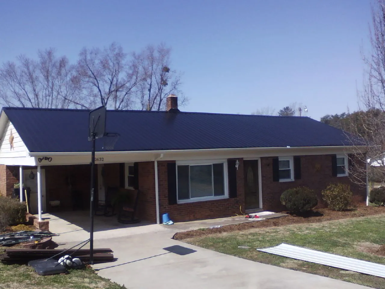 Finished dark blue metal roof on a brick ranch with a carport in Waskom
