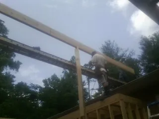 Carpenter setting a ridge beam over a new addition frame — Ice Dam Removal by Roofing Brothers in Waskom