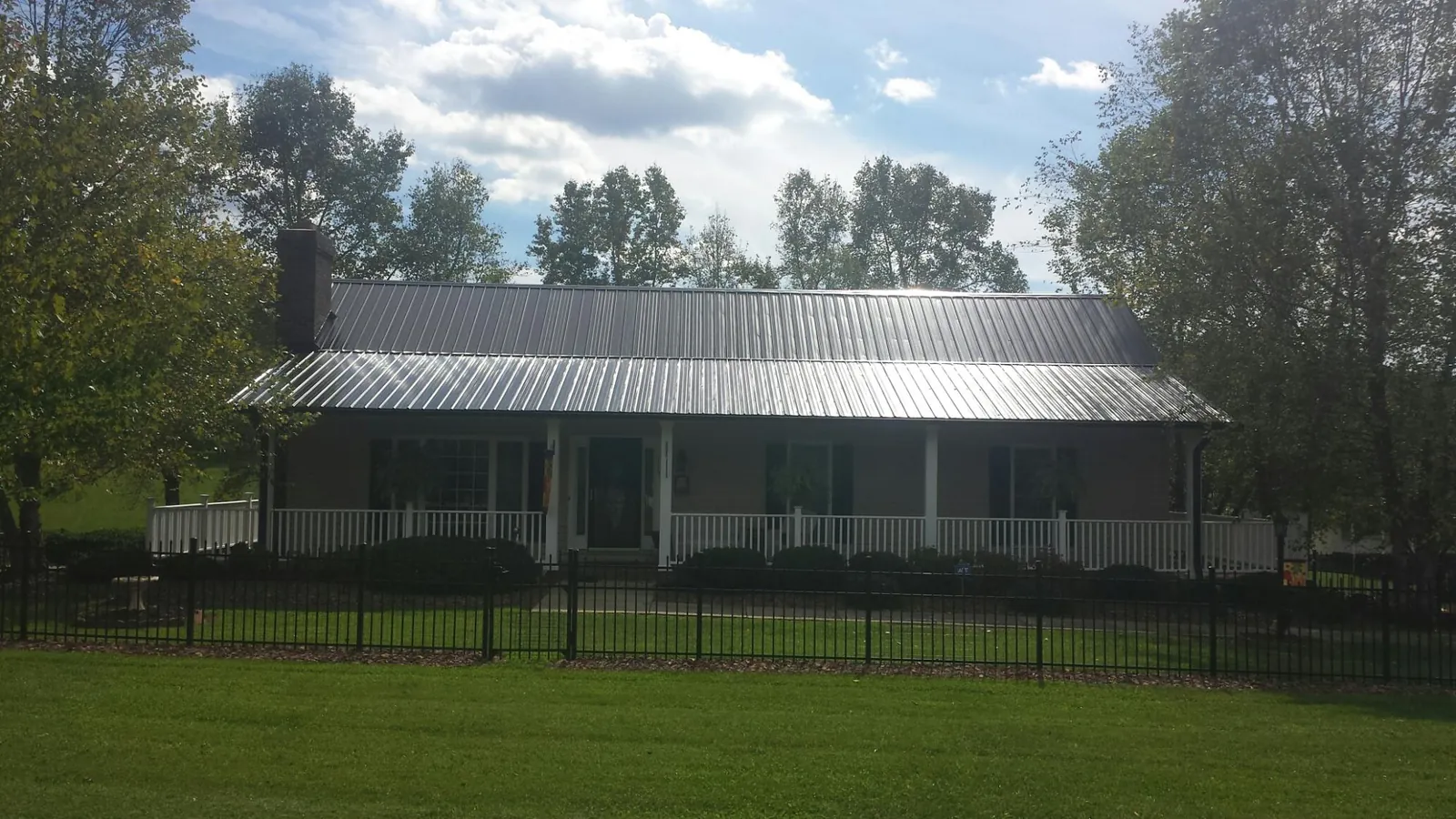 Gray metal roof on a brick ranch with a full width front porch — Gutter Guard Installation work by our crew in Waskom