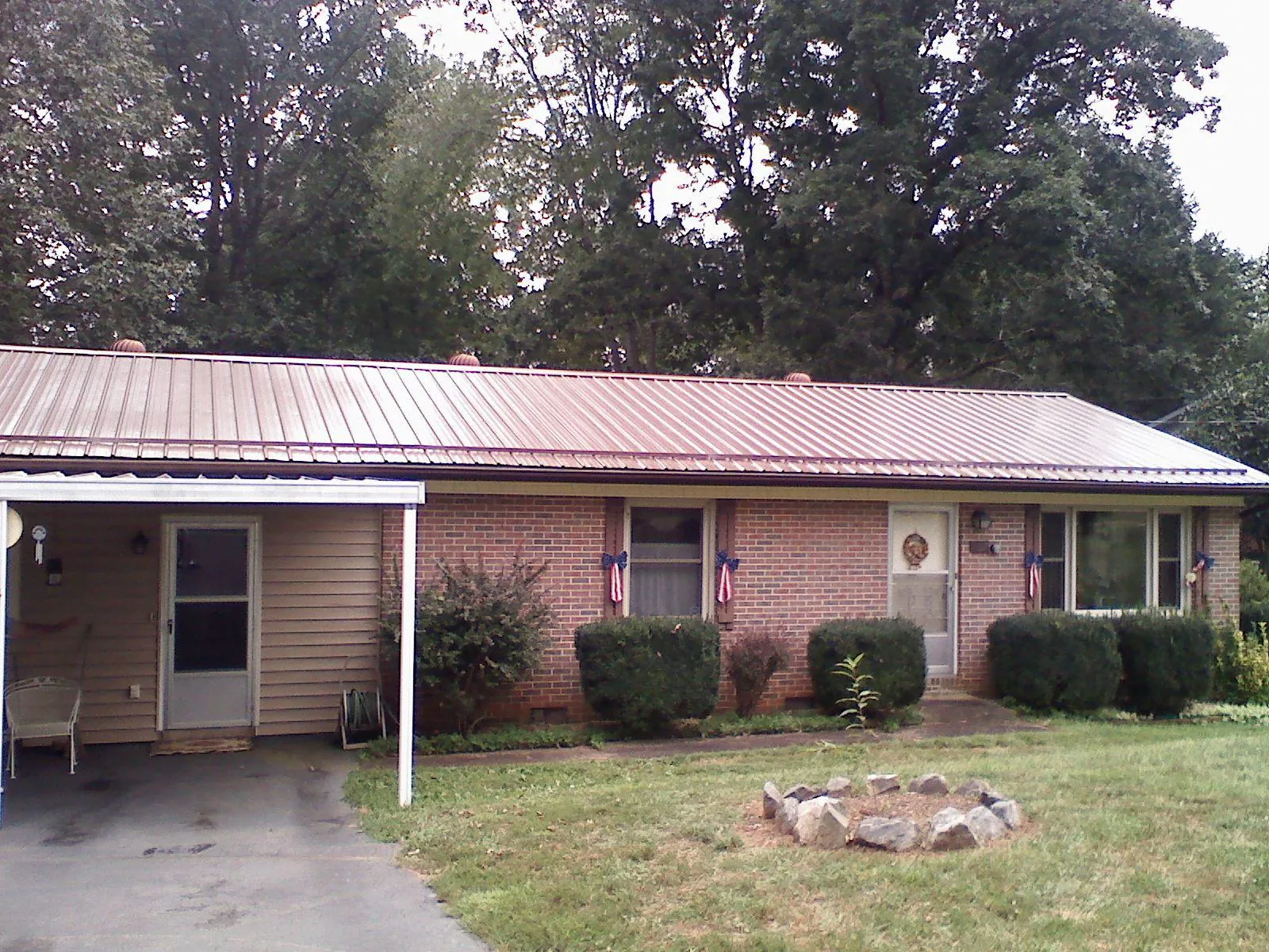 Bronze metal roof and carport on a brick ranch home — Roof Repair work by our crew in Waskom